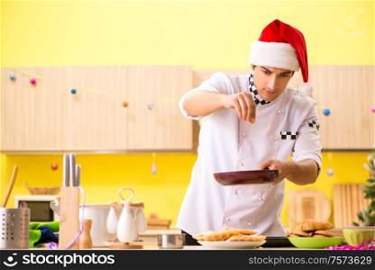 The young chef husband working in kitchen at christmas eve. Young chef husband working in kitchen at Christmas eve