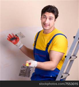 The young contractor employee applying plaster on wall. Young contractor employee applying plaster on wall
