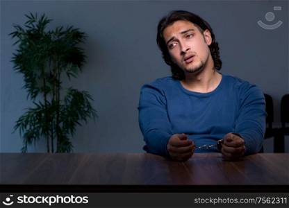 The young convict man sitting in dark room. Young convict man sitting in dark room