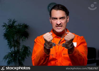 The young convict man sitting in dark room. Young convict man sitting in dark room