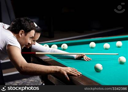 The young couple aim before blow in billiards