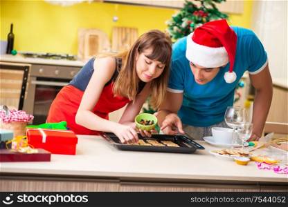 The young couple celebrating christmas in kitchen. Young couple celebrating Christmas in kitchen