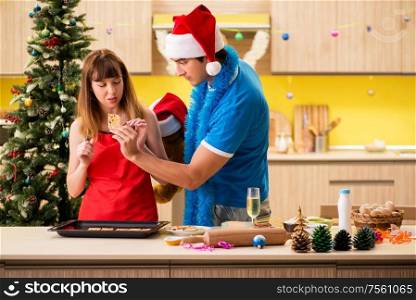 The young couple celebrating christmas in kitchen. Young couple celebrating Christmas in kitchen