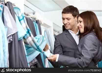 The young couple considers clothes in shop