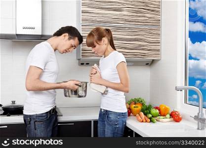 The young couple considers pan contents at kitchen