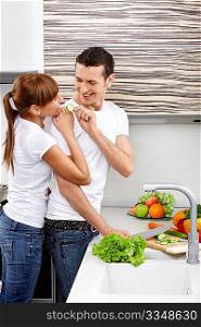 The young couple cuts vegetables at kitchen