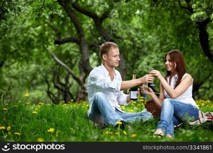 The young couple drinks champagne in wood