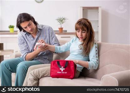 The young couple in first aid concept at home . Young couple in first aid concept at home 