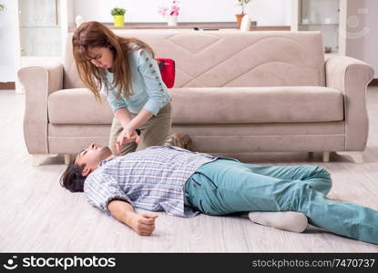 The young couple in first aid concept at home . Young couple in first aid concept at home 