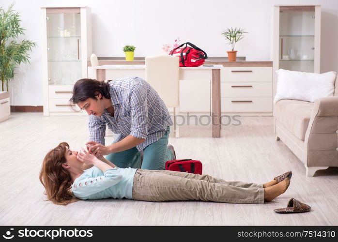 The young couple in first aid concept at home. Young couple in first aid concept at home