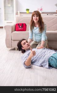 The young couple in first aid concept at home. Young couple in first aid concept at home