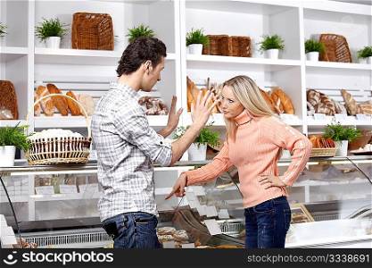 The young couple quarrels in a baker&acute;s shop