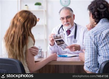 The young couple visiting old male doctor . Young couple visiting old male doctor 