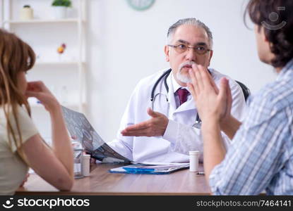 The young couple visiting old male doctor . Young couple visiting old male doctor