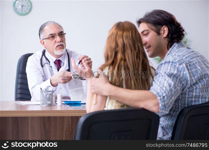 The young couple visiting old male doctor . Young couple visiting old male doctor