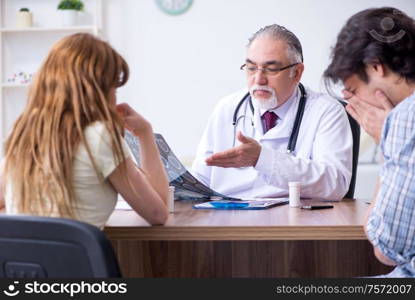 The young couple visiting old male doctor. Young couple visiting old male doctor