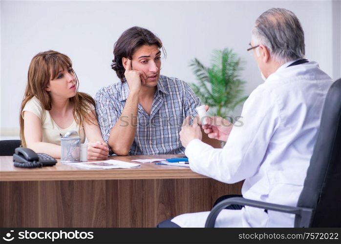The young couple visiting old male doctor. Young couple visiting old male doctor