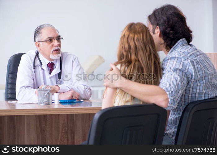 The young couple visiting old male doctor. Young couple visiting old male doctor