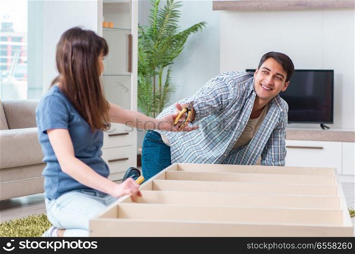 The young family assembling furniture at new house. Young family assembling furniture at new house