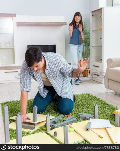 The young family assembling furniture at new house. Young family assembling furniture at new house