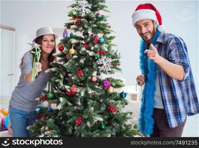 The young family decorating christmas tree on happy occasion. Young family decorating christmas tree on happy occasion