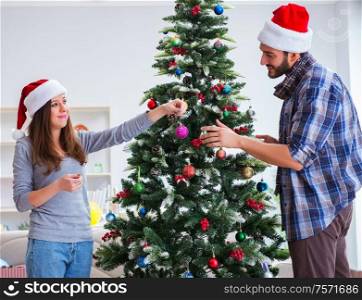 The young family decorating christmas tree on happy occasion. Young family decorating christmas tree on happy occasion