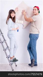 The young family doing renovation at home with new wallpaper. Young family doing renovation at home with new wallpaper