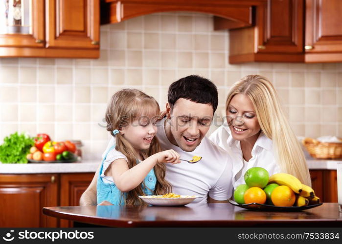 The young family has breakfast with the child on kitchen