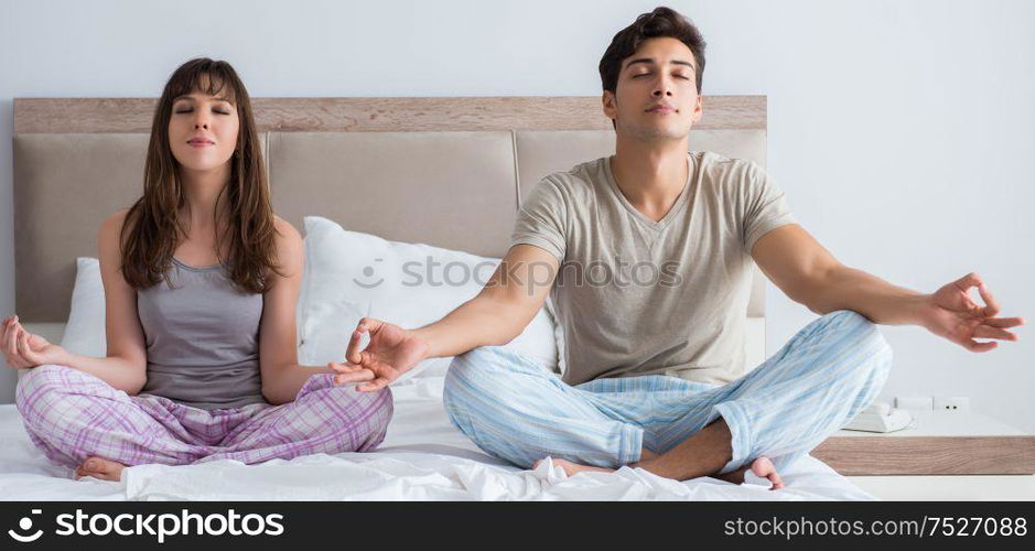 The young family meditating in the bed bedroom. Young family meditating in the bed bedroom