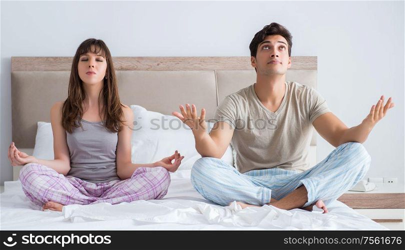 The young family meditating in the bed bedroom. Young family meditating in the bed bedroom