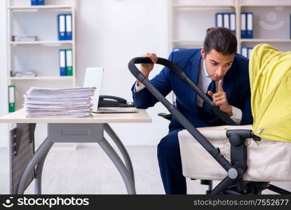 The young father looking after newborn in the office. Young father looking after newborn in the office