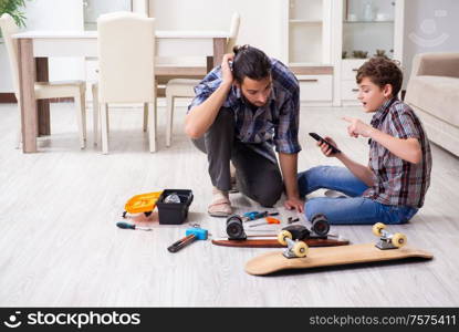 The young father repairing skateboard with his son at home. Young father repairing skateboard with his son at home