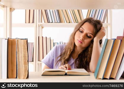 The young female student preparing for exams at library . Young female student preparing for exams at library 