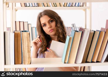 The young female student preparing for exams at library. Young female student preparing for exams at library