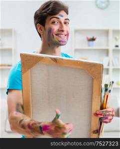 The young funny artist working on new painting in his studio. Young funny artist working on new painting in his studio