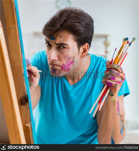 The young funny artist working on new painting in his studio. Young funny artist working on new painting in his studio
