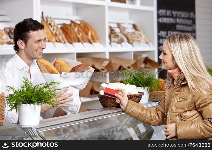 The young girl buys bread in shop