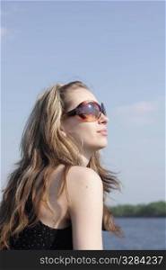The young girl in sunglasses on a forage of the yacht against the sky