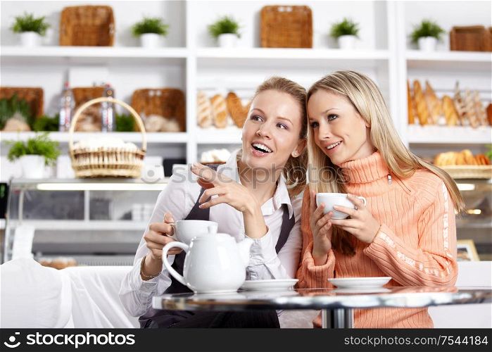 The young girl shows on something to the girlfriend in cafe