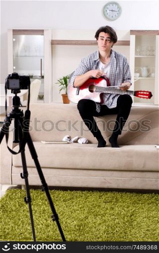The young guitar player recording video for his blog . Young guitar player recording video for his blog