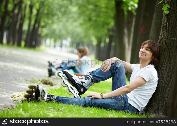 The young guy in rollers in the foreground in park