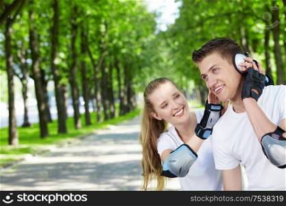The young guy with the girl in park listens to music