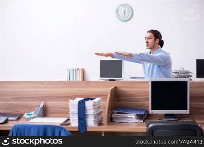 The young handsome businessman doing exercises at workplace. Young handsome businessman doing exercises at workplace