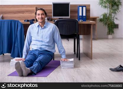 The young handsome businessman doing exercises at workplace. Young handsome businessman doing exercises at workplace