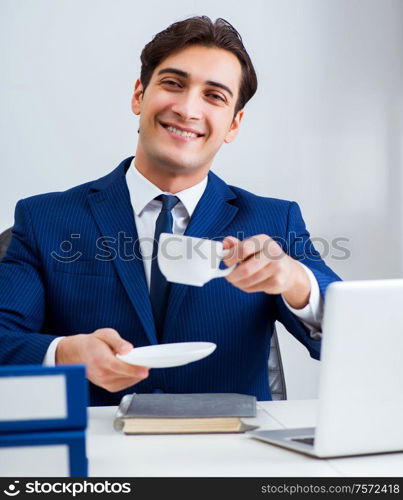 The young handsome businessman employee working in office at desk. Young handsome businessman employee working in office at desk