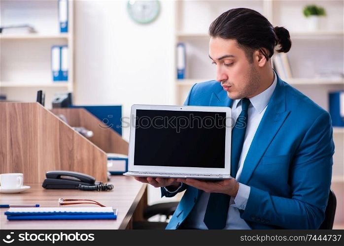 The young handsome businessman sitting in the office . Young handsome businessman sitting in the office 