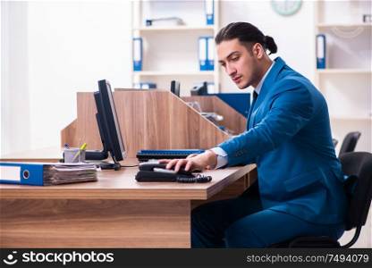 The young handsome businessman sitting in the office. Young handsome businessman sitting in the office