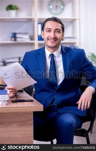 The young handsome businessman working in the office . Young handsome businessman working in the office