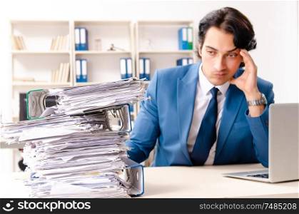 The young handsome busy employee sitting in office . Young handsome busy employee sitting in office