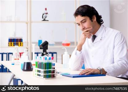 The young handsome chemist working in the lab . Young handsome chemist working in the lab
